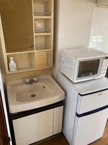 a kitchen with a sink and a microwave on top of a refrigerator at Oita City Vacation Condominium in Oita