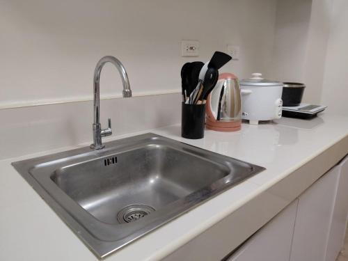 a stainless steel kitchen sink with utensils in a holder at SMDC Trees Residences Jim's Staycation in Manila