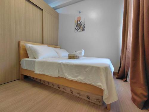 a bedroom with a bed with white sheets and pillows at SMDC Trees Residences Jim's Staycation in Manila