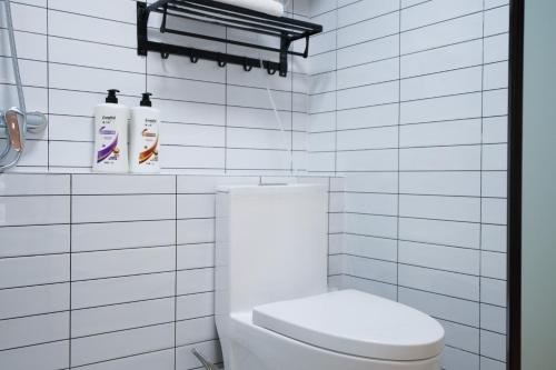 a white tiled bathroom with a toilet and two shampoo bottles at Funx设计师民宿 in Chengdu