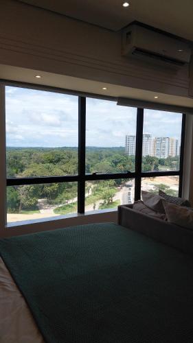 a bedroom with a large window with a view of the city at Tropical Executive Suite Flat 1001 Veiw in Manaus