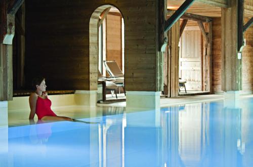 a woman sitting on the floor of a swimming pool at Chalet-Hôtel La Marmotte, La Tapiaz & SPA, The Originals Relais (Hotel-Chalet de Tradition) in Les Gets
