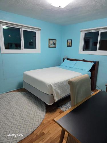 a blue bedroom with a bed and a table at Gary's Place in Springfield
