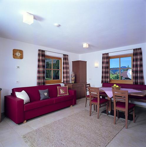 a living room with a red couch and a table at Apartments Restaurant Rusctlea in Selva di Val Gardena