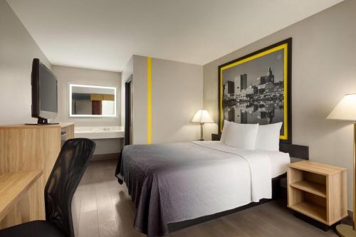 a hotel room with a bed and a television at Super 8 by Wyndham Meadowlands in Carlstadt