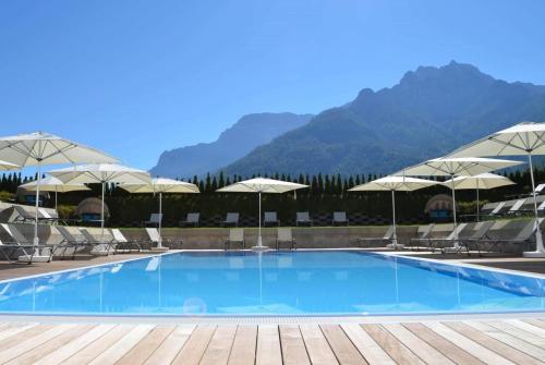 a swimming pool with chairs and umbrellas at KUHOTEL Steinplatte, Trademark Collection by Wyndham in Waidring