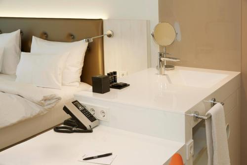 a white bathroom with a sink and a bed at elaya hotel kleve, Trademark Collection by Wyndham in Kleve