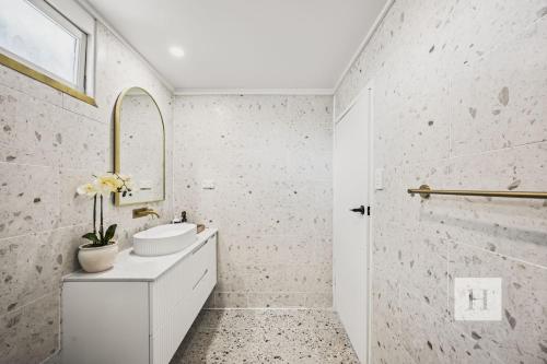 a white bathroom with a sink and a mirror at Sunset Shore Retreat in Summerland Point