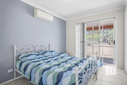 a bedroom with a bed with a blue and white comforter at Jilliby Honey Farm in Jilliby