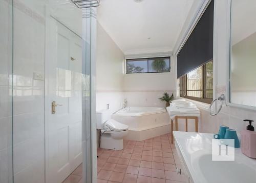 a bathroom with a tub and a toilet and a sink at Tide view in Toukley