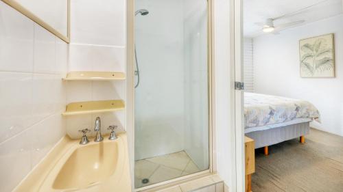 a bathroom with a tub and a shower and a bed at Merrima Court Holidays in Caloundra
