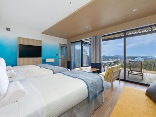 a hotel room with two beds and a large window at Wan Wan Paradise Premier Nanki Shirahama in Shirahama