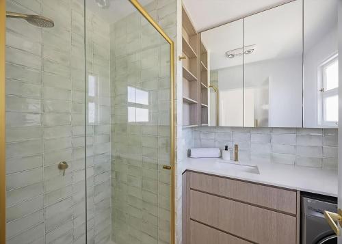 a bathroom with a glass shower and a sink at Frangipani Hideaway in Budgewoi