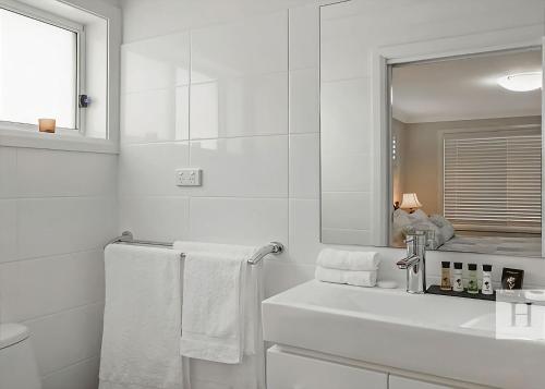 a white bathroom with a sink and a mirror at Enjoy Lazy Daze in Summerland Point
