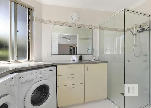 a white bathroom with a washing machine and a shower at Karinyah in Summerland Point