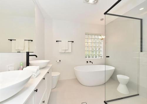 a white bathroom with two sinks and a tub at Lake Daze at Coal Point in Coal Point