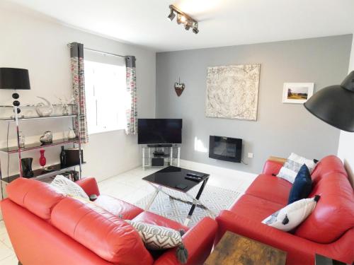 a living room with a red couch and a tv at Railway Cuttings in Falstone