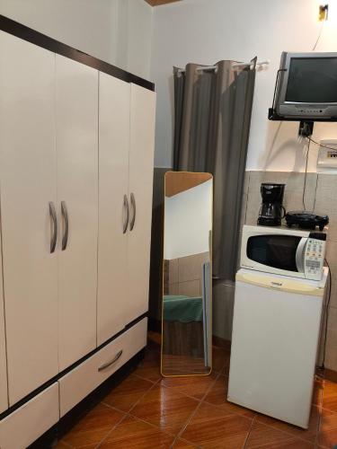 a small kitchen with a microwave and a refrigerator at Microcasa Caledônia Nova Friburgo in Nova Friburgo