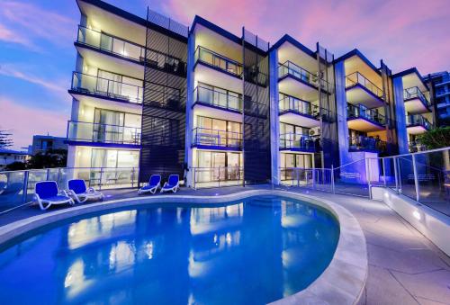 a swimming pool in front of a building at Merrima Court Holidays in Caloundra