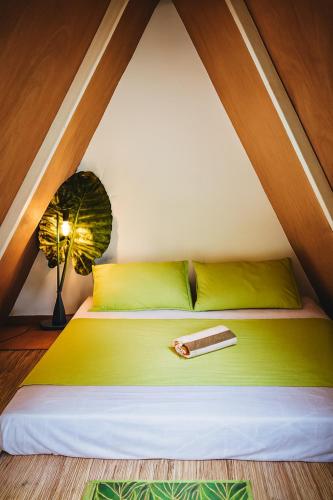 a bedroom with a green bed with a lamp at Kapsula El Nido in El Nido