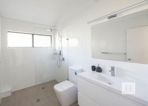 a white bathroom with a toilet and a sink at Lakeshores Villa in Cams Wharf