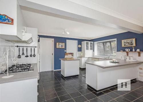 a large kitchen with white appliances and blue walls at Mannering Lake House in Mannering Park