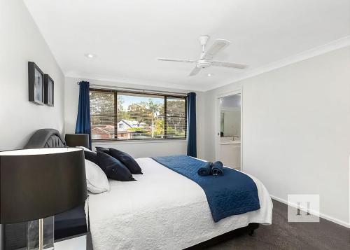 a bedroom with a bed and a ceiling fan at Mannering Lake House in Mannering Park