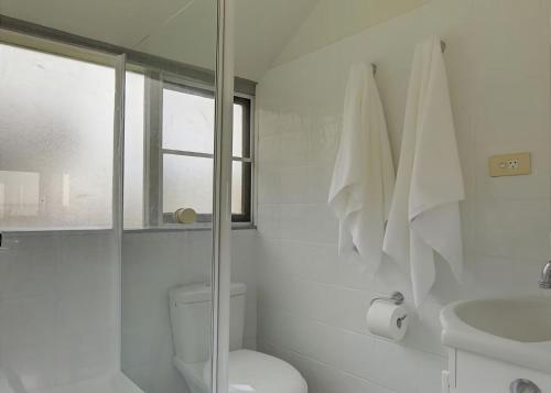 a white bathroom with a toilet and a sink at Norah Beach Shack 1 in Norah