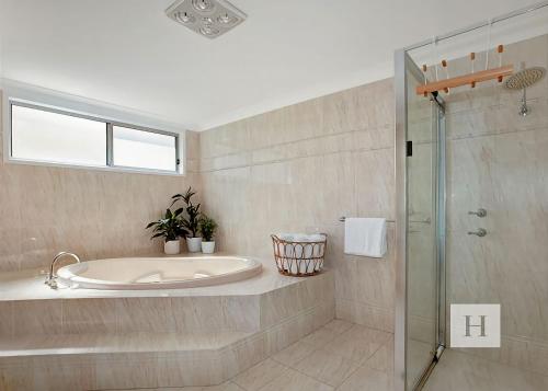 a bathroom with a tub and a glass shower at Niaroo Lakeside in Summerland Point