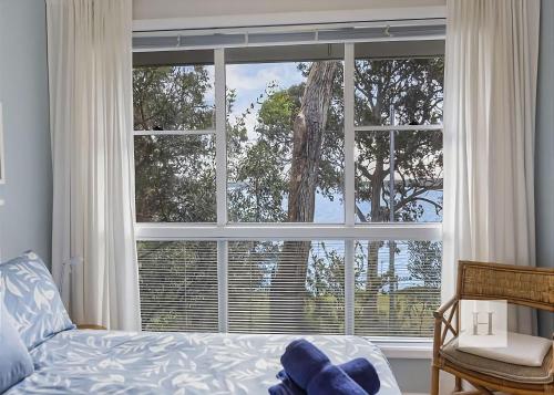 a bedroom with a large window and a bed and a chair at Relaxing Getaway in Summerland Point