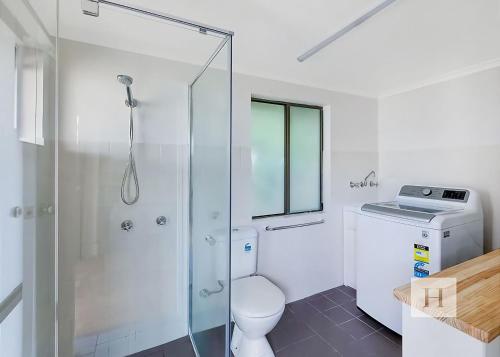 a bathroom with a toilet and a glass shower at Paradise Palms in Mannering Park