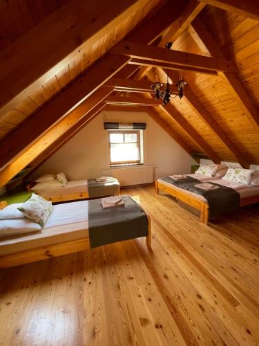 two beds in a attic room with a window at Panoráma Villa Vágáshuta in Vágáshuta