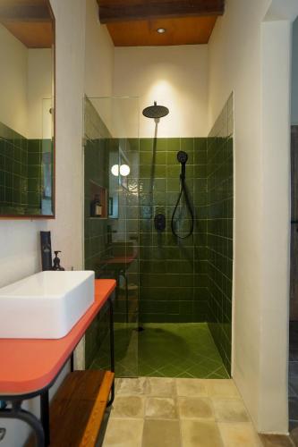 a bathroom with a sink and a shower with green tiles at Songbird Boutique Inn in Canggu