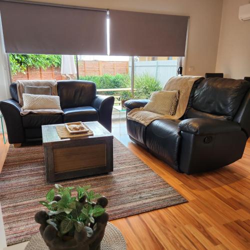 a living room with a leather couch and a table at Lbarza Charming Central 2BR Townhouse in Shepparton
