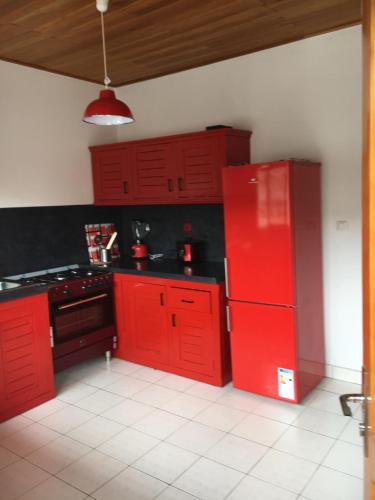 a red kitchen with black counters and red cabinets at Nandy's home in Odza II