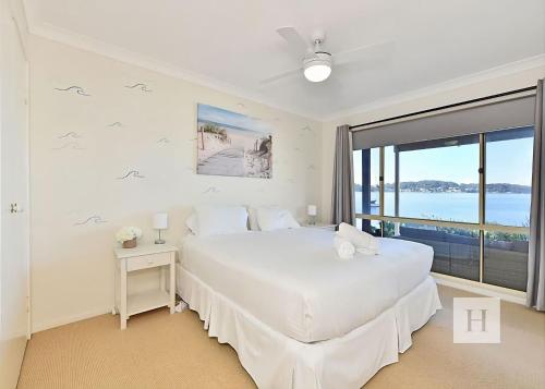 a white bedroom with a bed and a large window at Sparkling Waters in Rathmines