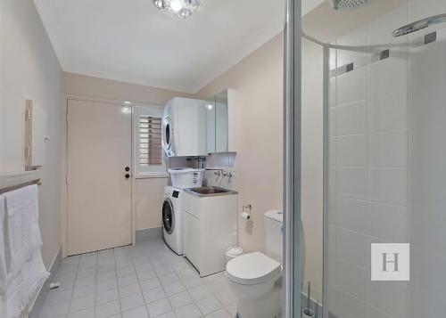 a white bathroom with a toilet and a refrigerator at Sunset Lakehouse in Toukley