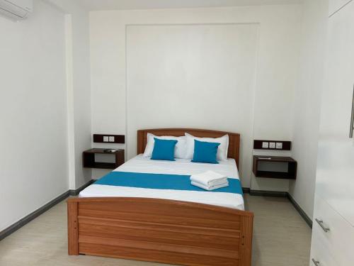 a bedroom with a large bed with blue pillows at Hillkandy in Kengalla