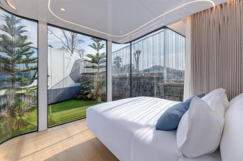 a bedroom with a white bed and a large window at Air Space Camp Khao Yai in Pak Chong