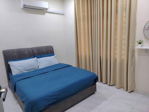 a bedroom with a bed with blue sheets and a window at Infra Homestay 1 in Marang