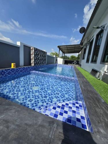 a swimming pool with a blue and white tile floor at Infra Homestay 1 in Marang