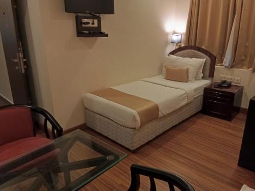 a hotel room with a bed and a glass table at Hotel Gentleman Mithila in Eramalloor