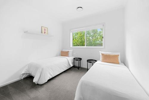 two beds in a room with white walls and a window at Spacious 4-Bedroom Retreat in Mansfield
