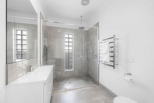 a white bathroom with a shower and a sink at Spacious 4-Bedroom Retreat in Mansfield