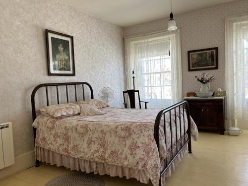 a bedroom with a bed and a table and a window at Manoir Hamilton in New Carlisle