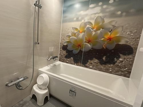 a bathroom with a toilet and a picture of flowers at Hotel Maile in Tokyo