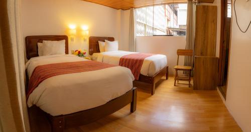 a hotel room with two beds and a window at Seven Machupicchu in Machu Picchu