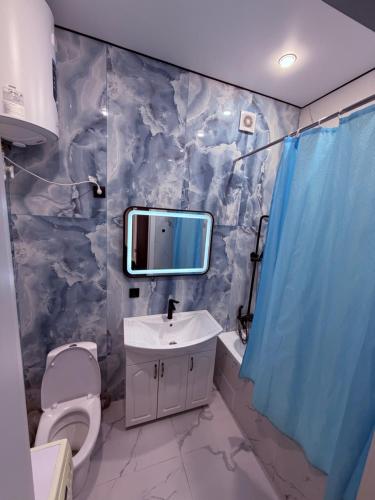 a bathroom with a toilet and a sink and a mirror at Atamura 1 in Karagandy