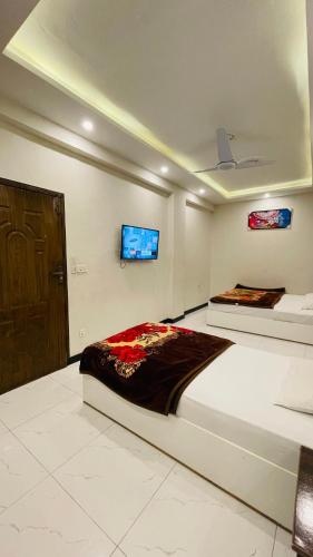 a bedroom with two beds and a tv on the wall at Peace Continental Hotel in Islamabad