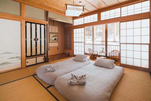 two beds in a room with large windows at Ao No Mori in Myoko